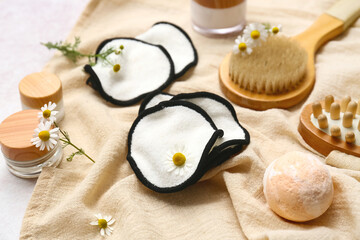 Cotton pads, bath supplies and flowers on light background, closeup