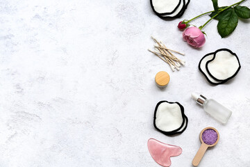 Cotton pads, flowers, guasha and bath supplies on light background