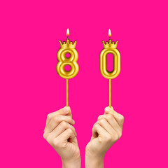 Birthday on a fuchsia background with the number 80 - Hands holding number-shaped candles