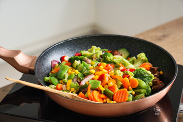 Frying pan with tasty vegetables on stove in kitchen, closeup