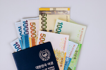 Stack of South Korean won banknotes arranged with dark Korean passport, showcasing currency identity together.