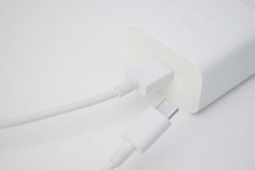 White USB-C charger adapter with charging cable on clean white background, modern electronic accessory concept.
