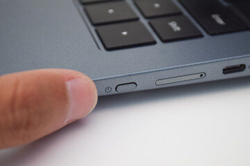 Finger pressing laptop power button, concept of technology usage, device startup, control, and modern electronics.