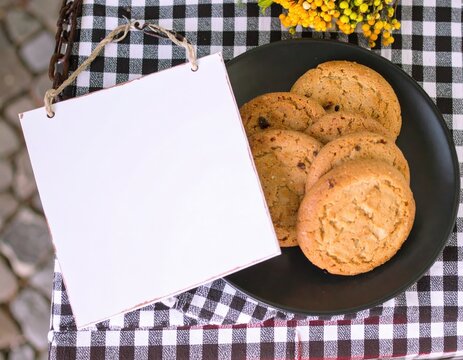 Cookies and Blank Sign on Checkered Tablecloth for Bakery Ad.