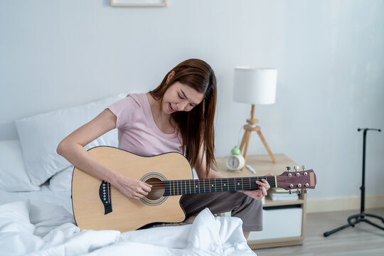 Asian beautiful woman musician playing an acoustic guitar in house. - Powered by Adobe