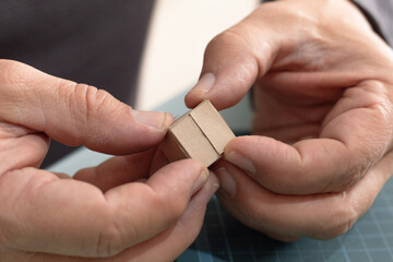 Adult hands assembling a miniature box holding tabs. Cardboard craftsmanship without visible glue, concept of packaging and creative recycling