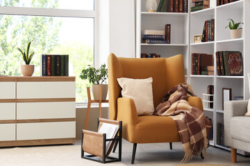 Interior of stylish living room with brown armchair and bookshelf