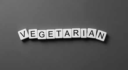 Close-up shot of the word 'Vegetarian' spelled out with white letter tiles on a gray surface.