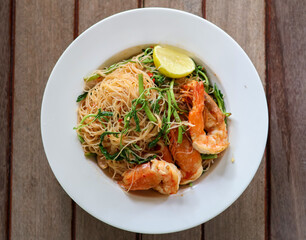 Top view of Stir-fried Vermicelli with Water Mimosa with shrimps in plate on wooden background