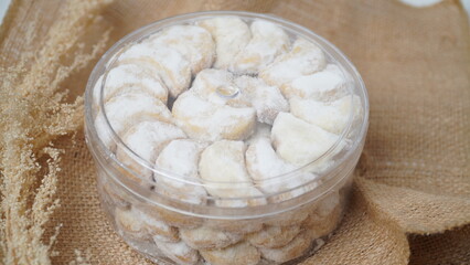 Homemade Putri Salju cookies coated in powdered sugar, stored in a transparent jar. Shot on a clean white background, perfect for festive food promotions and design assets