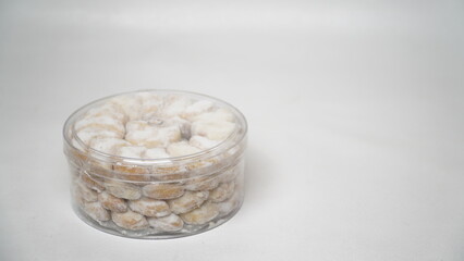 Homemade Putri Salju cookies coated in powdered sugar, stored in a transparent jar. Shot on a clean white background, perfect for festive food promotions and design assets