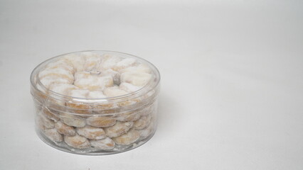 Homemade Putri Salju cookies coated in powdered sugar, stored in a transparent jar. Shot on a clean white background, perfect for festive food promotions and design assets