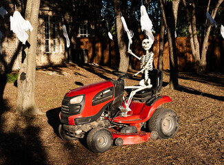 Halloween Lawn skeleton driving a lawn mower on way to Trick or Treat in October