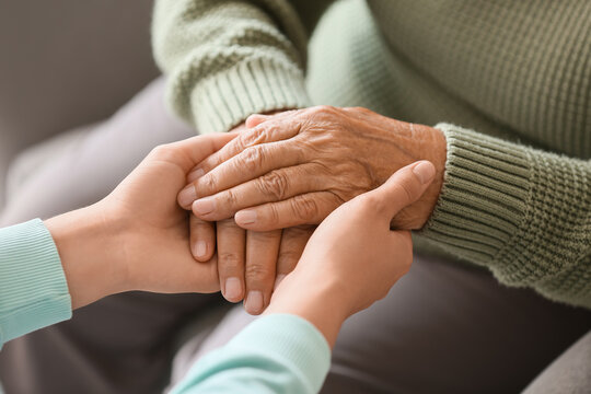 Woman holding grandmother's hands at home, closeup