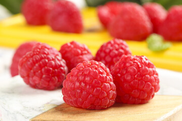 Fresh Red Raspberries on Wooden Board with Colorful Fruit Background