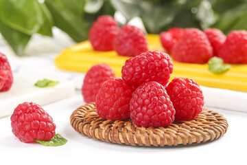 Fresh Red Raspberries on Wicker Plate with Colorful Spring Fruits and Flowers Background