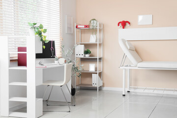 Interior of gynecologist's office with workplace, couch and shelf unit