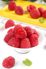 Fresh Red Raspberries in White Bowl with Shallow Focus and Mint Garnish