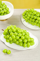 Fresh Green Grapes on White Plates with Sunny Yellow Background - Healthy Fruit Display