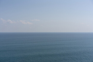 A minimalist and serene seascape featuring the calm blue ocean meeting a soft, hazy sky. A perfect, peaceful, and atmospheric nature background.
