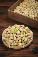 Fresh Pistachios in Wicker Basket on Wooden Background - Healthy Nuts and Snack Food