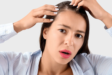 Naklejka premium Worried young woman with hair loss problem on light background, closeup