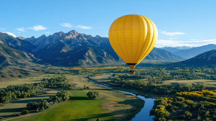 Fototapeta premium Vibrant yellow hot air balloon floats gracefully over scenic valley, surrounded by majestic