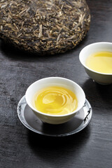 Traditional Chinese Tea Ceremony with Pu-erh Tea Cake and Golden Tea in Porcelain Cups