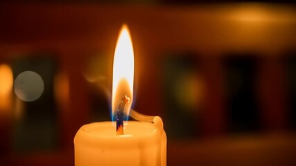 A close-up of a flickering candle flame with smoke rising, set against a warm, blurred background - Powered by Adobe