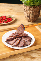 Sliced Corned Beef on White Plate with Chopsticks and Fresh Vegetables on Wooden Kitchen Table