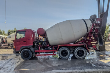 Red concrete mixer truck at construction site, industrial vehicle used to transport and mix cement...