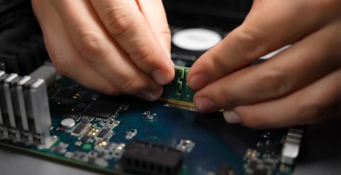 Hands installing ram module into computer motherboard slot