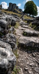 A close-up view of a weathered stone path leading upward, with large rocks framing the walkway and a historical stone structure in the background.