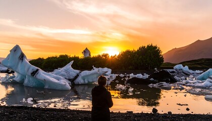 Person watching a beautiful sunset over a glacial lagoon with icebergs.