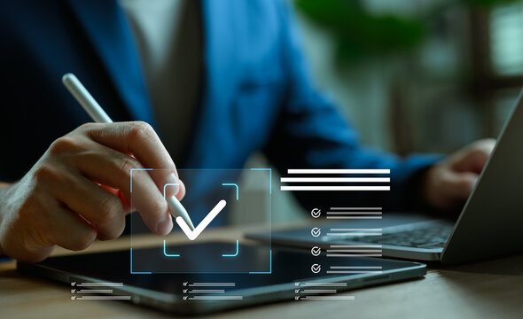 Digital checklist concept. Businessman using stylus to mark check symbol on tablet screen. Project planning, task management, to-do list and productivity technology in workplace.