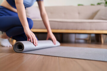 Adult Asian woman rolling yoga mat home living room fitness workout routine preparing exercise wellness healthy lifestyle