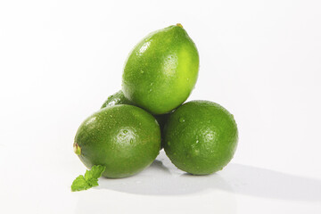 Fresh Green Hainan Limes with Water Droplets and Mint Leaf on White Background