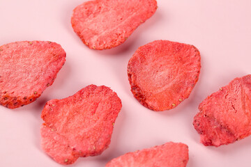Freeze-dried strawberry slices on pink background - healthy fruit snacks and natural food concept