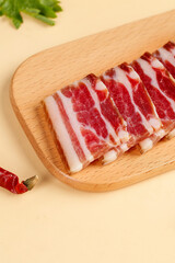 Raw Bacon Slices on Wood Cutting Board with Fresh Herbs and Spices