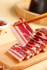 Sliced Pancetta Bacon with Chopsticks on Wooden Cutting Board - Traditional Cured Pork Meat Preparation