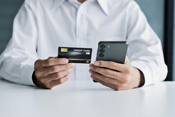 Adult male using smartphone and credit card to complete secure digital payment and banking transaction online