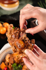 Tender Braised Oxtail with Rich Sauce Being Held by Hands - Traditional Comfort Food Dish