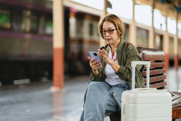 Female traveler using smartphone at train station