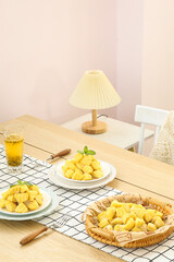 Fresh Cooked Potatoes on Wooden Dining Table with Modern Lamp and Tea Glass in Kitchen Interior