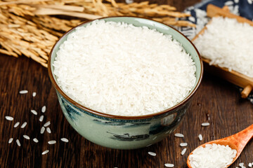 White rice in ceramic bowl with wooden spoon on rustic table - Asian food ingredient closeup