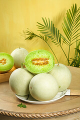 Fresh Honeydew Melons with Jade Green Flesh on Wooden Table with Palm Leaves