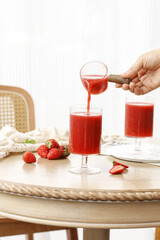 Fresh Strawberry Juice Being Poured into Glass with Berries on Wooden Table - Refreshing Summer Drink