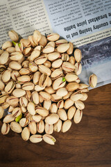 Fresh Green Pistachios Kernels on Wooden Table with Newspaper Background