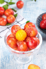 Fresh Red and Yellow Plums from Guangdong China in Glass Bowl with Water Droplets on Wooden Table