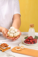 Handmade cheese balls with red dates almonds milk and creamy spreads on wood marble kitchen counter